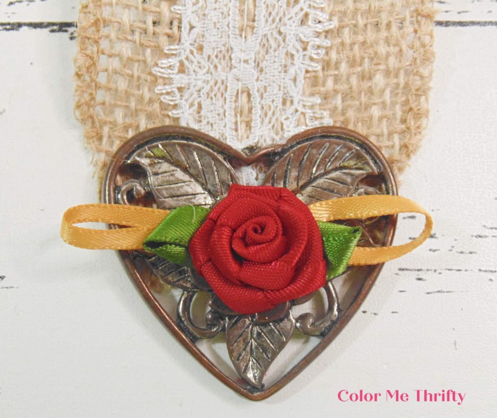 gluing large heart pendant on bottom of paper heart wall hanging.